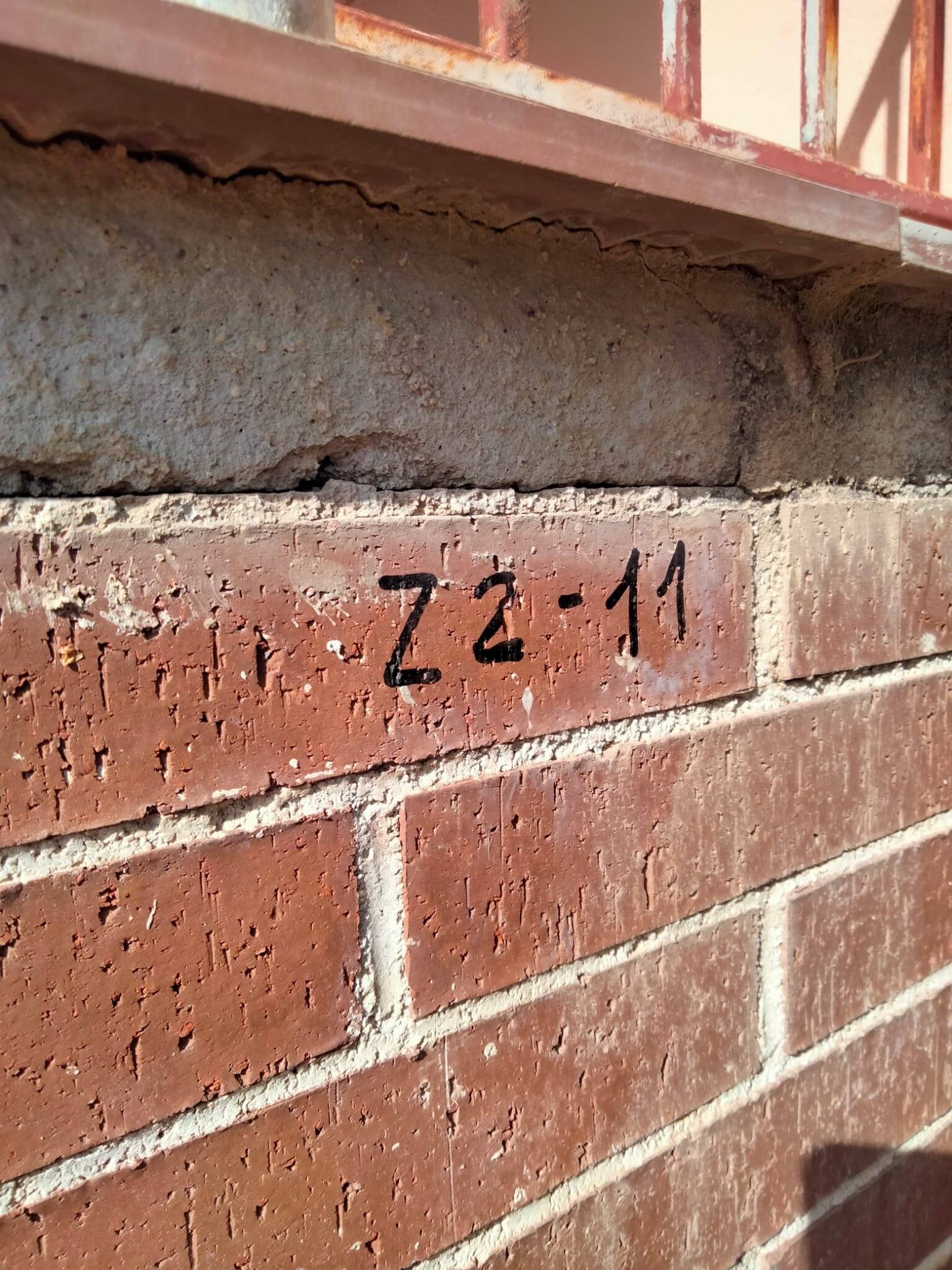 Cerramiento de ladrillo separado del canto del forjado por una abertura horizontal, con la marca de punto de inyección «Z2-11» pintada en la fábrica.