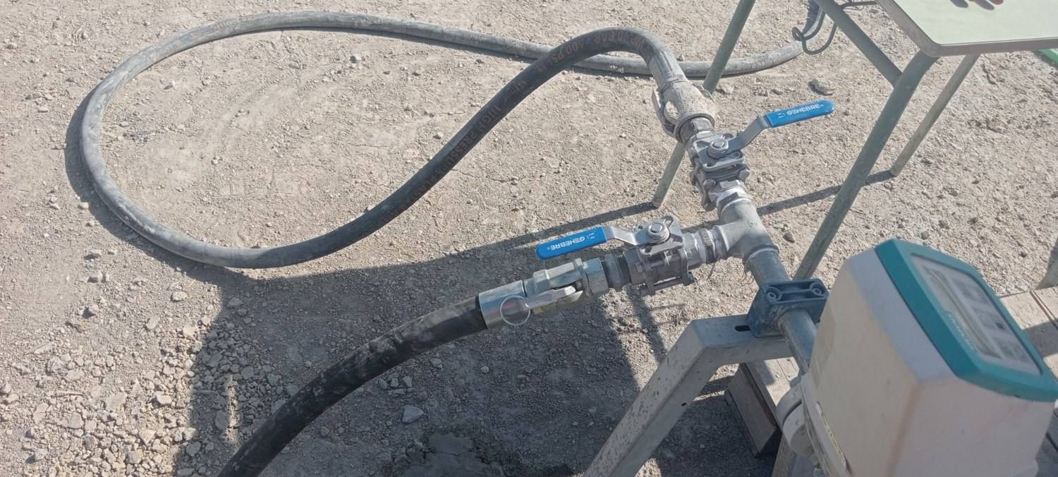 Mangueras de inyección conectadas a un colector con dos llaves de bola y un caudalímetro, sobre el terreno del solar.