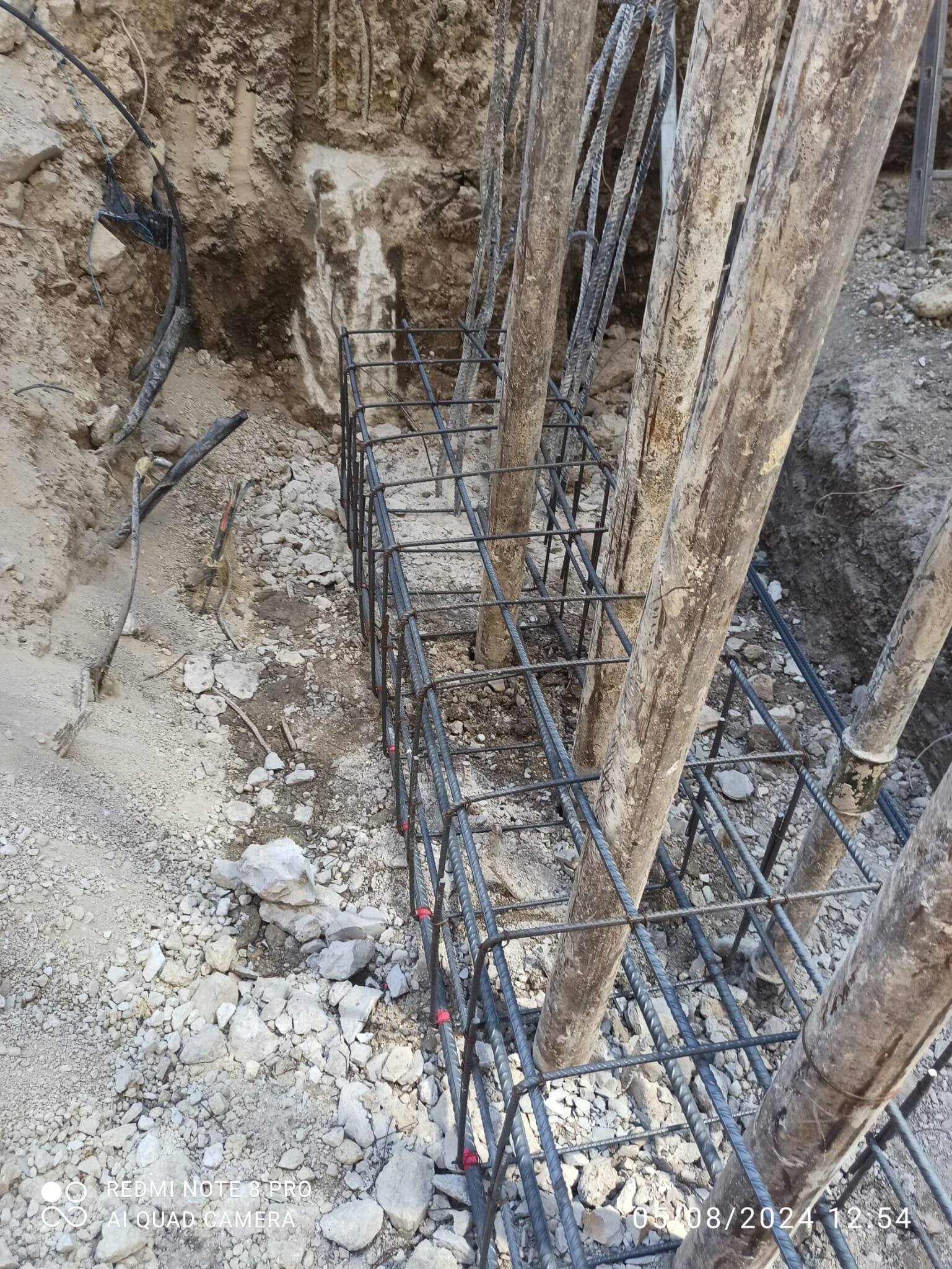 Micropile wall exposed in the excavation, with the reinforcement of the capping beam fixed at its foot.