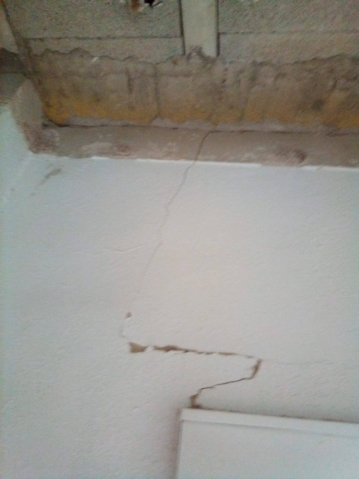 Grieta escalonada en un tabique interior que nace en la esquina superior de una ventana.